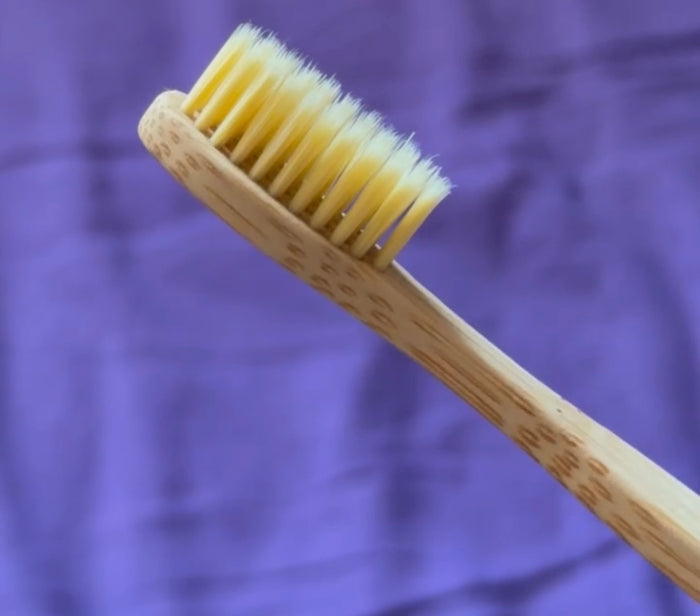 Main déposant une goutte d'huile sur une brosse en bambou.